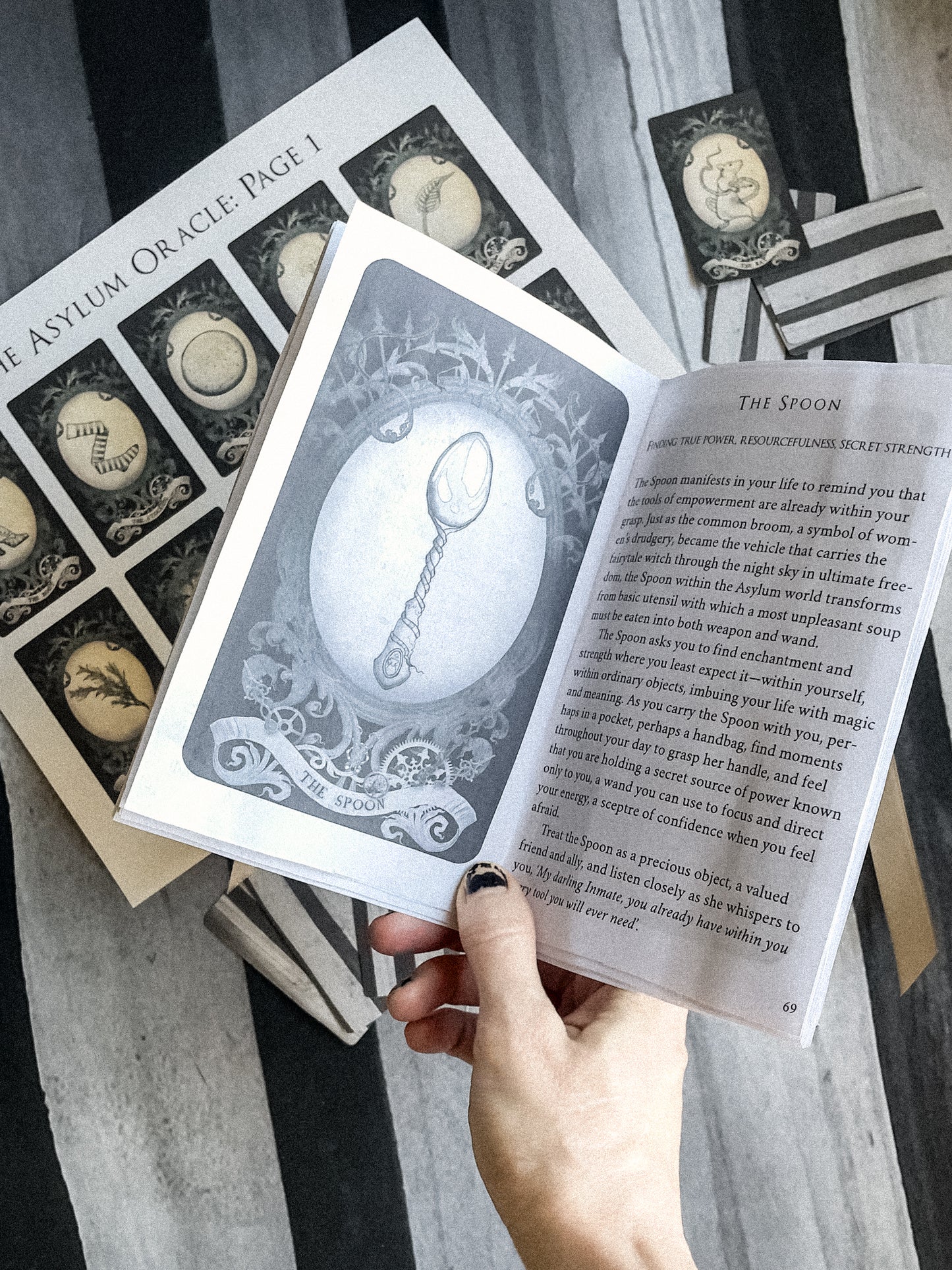 Collection of oracle cards with a spoon illustration and text, held by a hand.