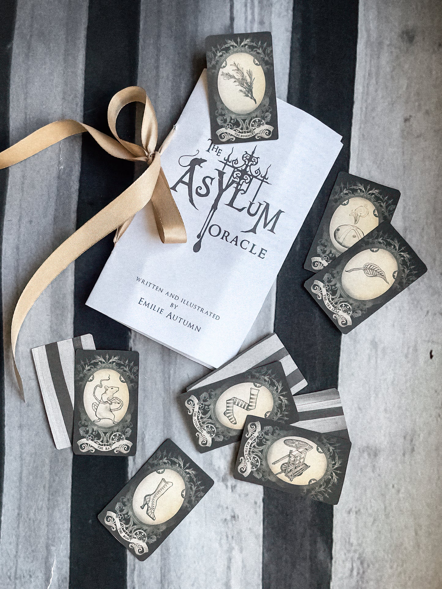 Oracle cards from 'The Asylum Oracle' with a ribbon on a striped background