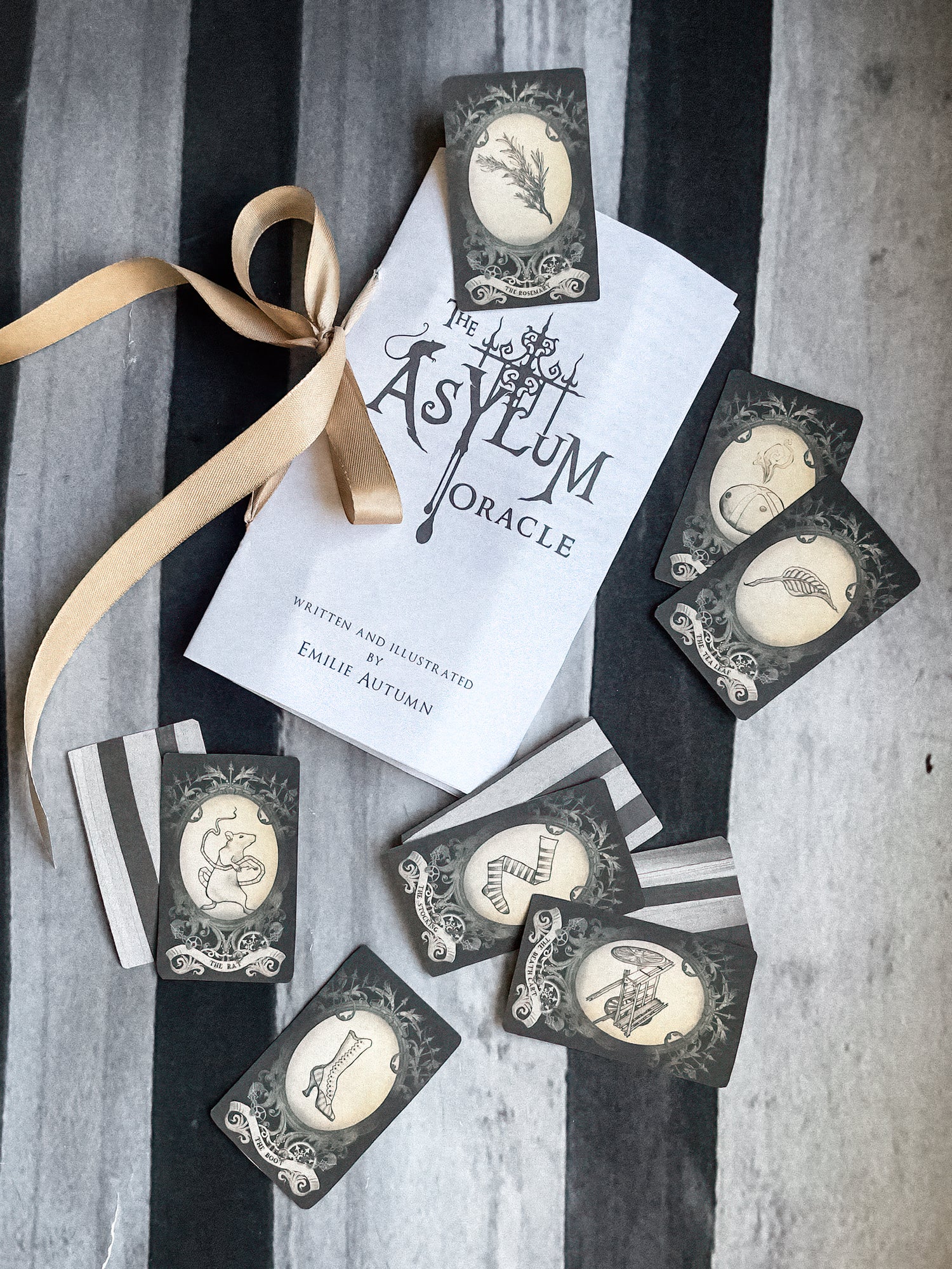 Oracle cards from 'The Asylum Oracle' with a ribbon on a striped background