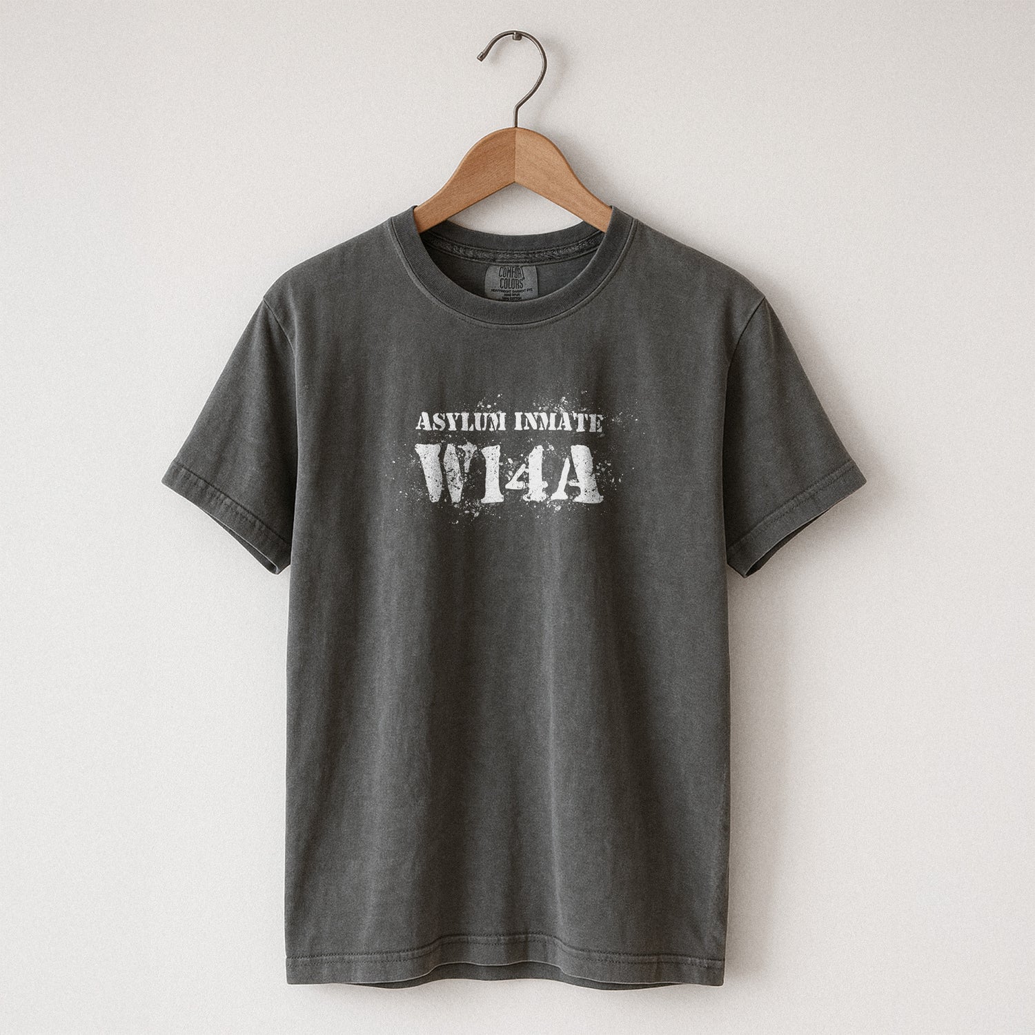 Pepper Comfort Colors  t-shirt with 'ASYLUM INMATE W14A' text on a hanger against a white background