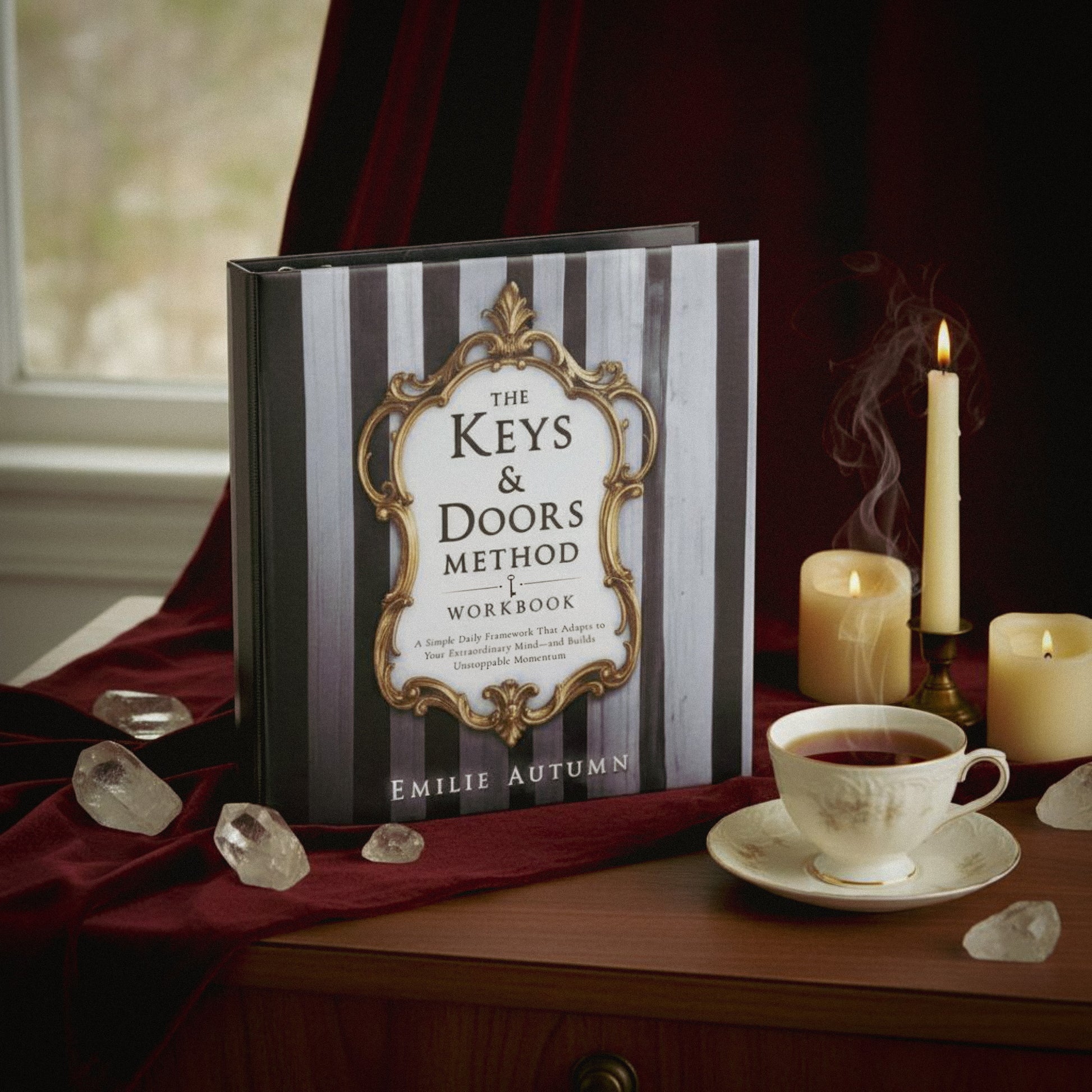 Book titled 'The Keys & Doors Method Workbook' by Emilie Autumn on a table with candles and tea.